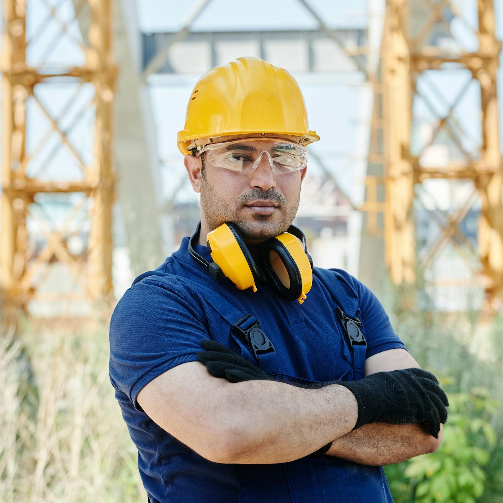 Confident engineer standing with protective gear at a construction site.